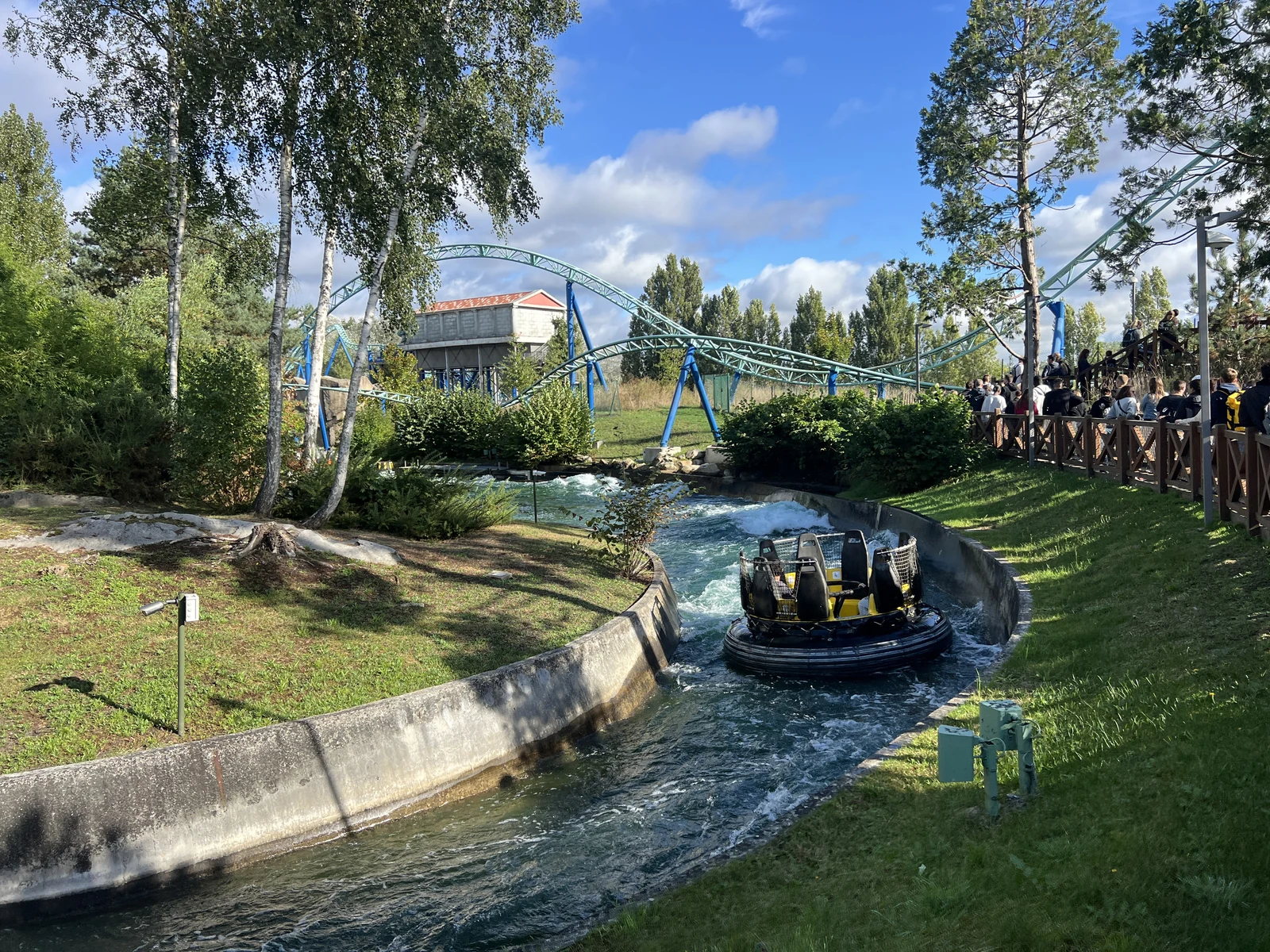Une bouée avec des visiteurs, des rails bleus et la végétation du Parc Astérix