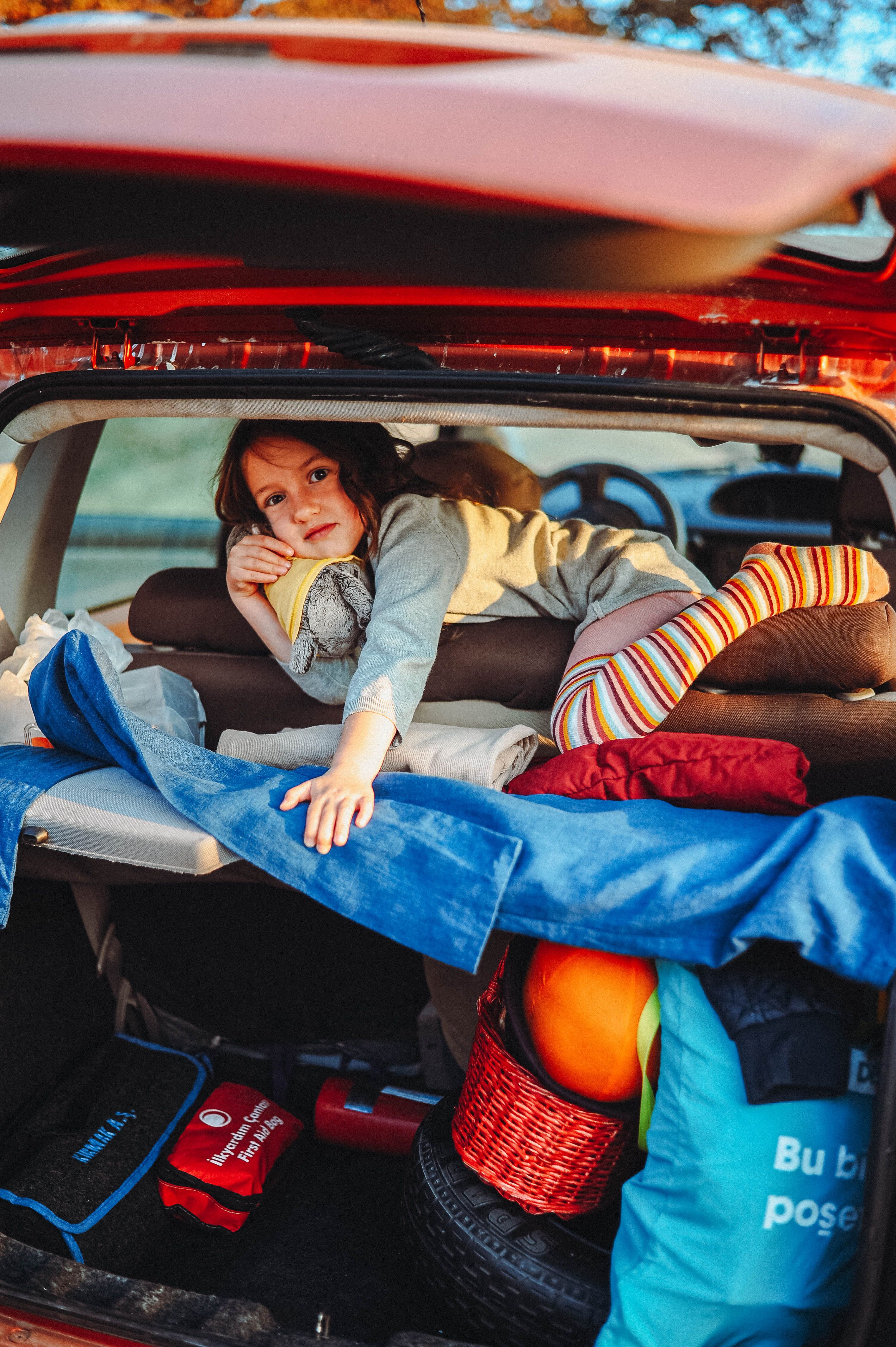 Enfant et bagages installés dans le coffre avant un départ en voiture