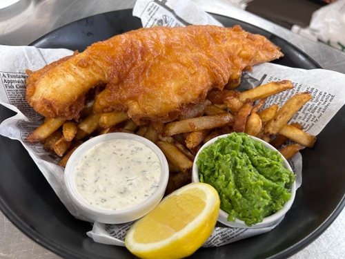 Fish and chips britannique servi avec petits pois et citron