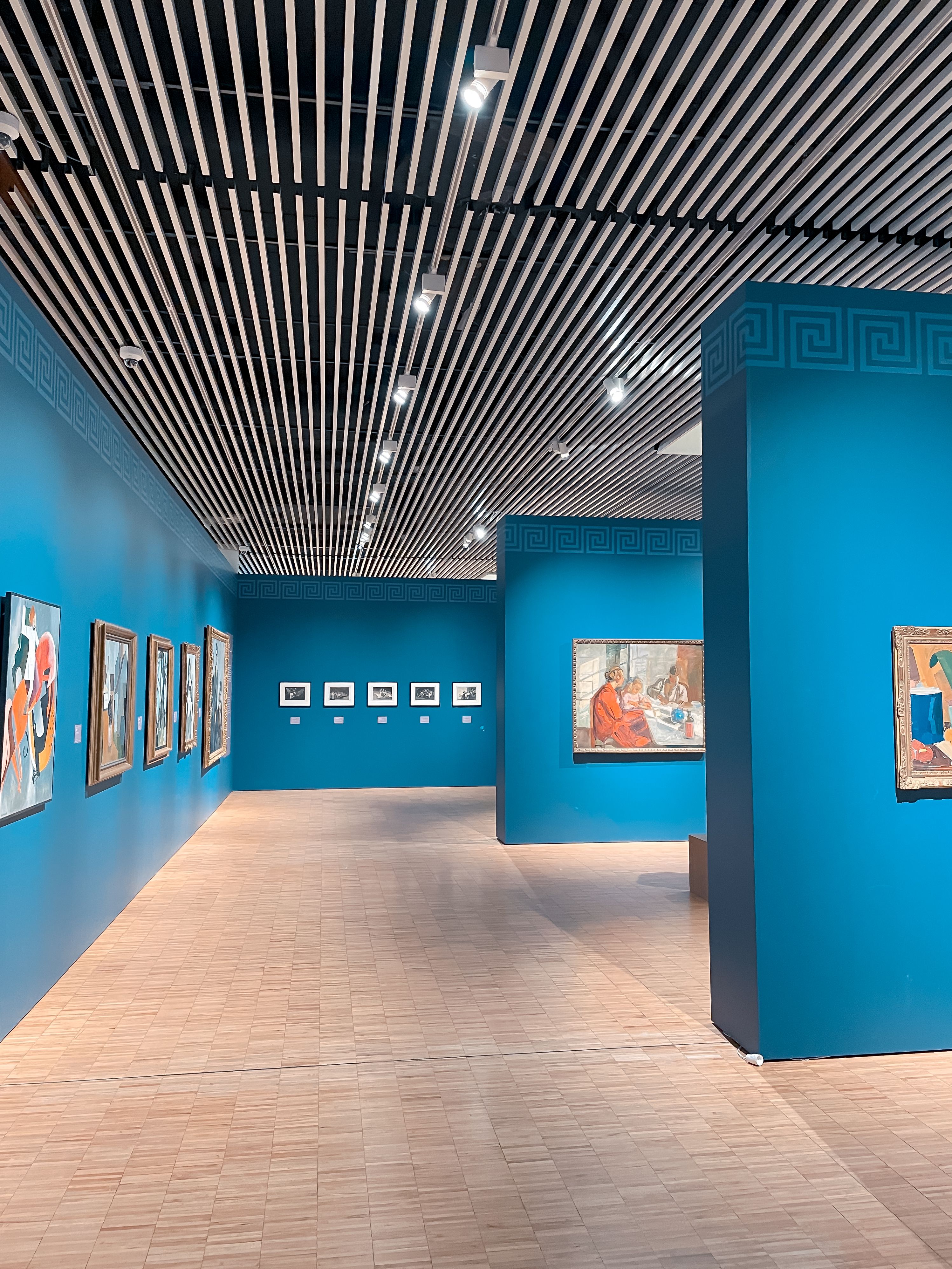 Galerie de musée aux murs bleus présentant des peintures colorées